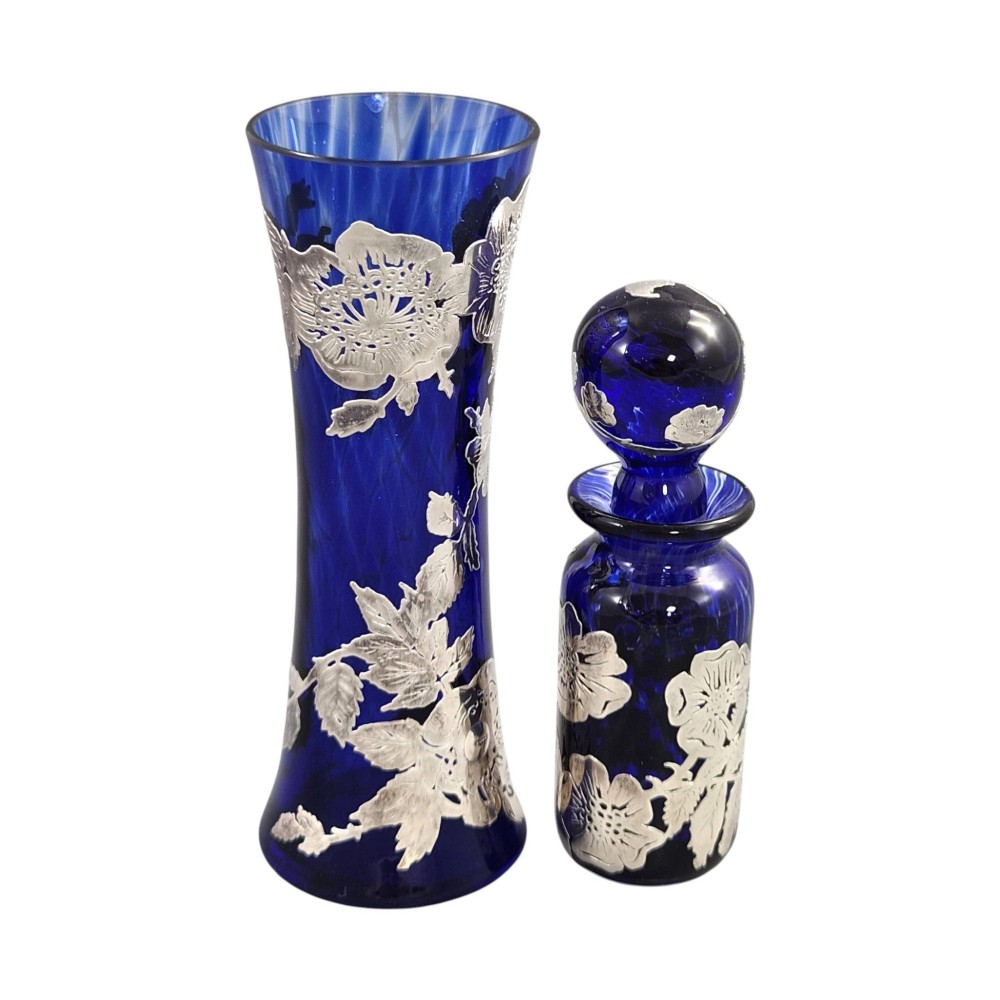 A cobalt blue glass vase and matching perfume bottle with stopper, both featuring intricate sterling silver floral overlay. View V