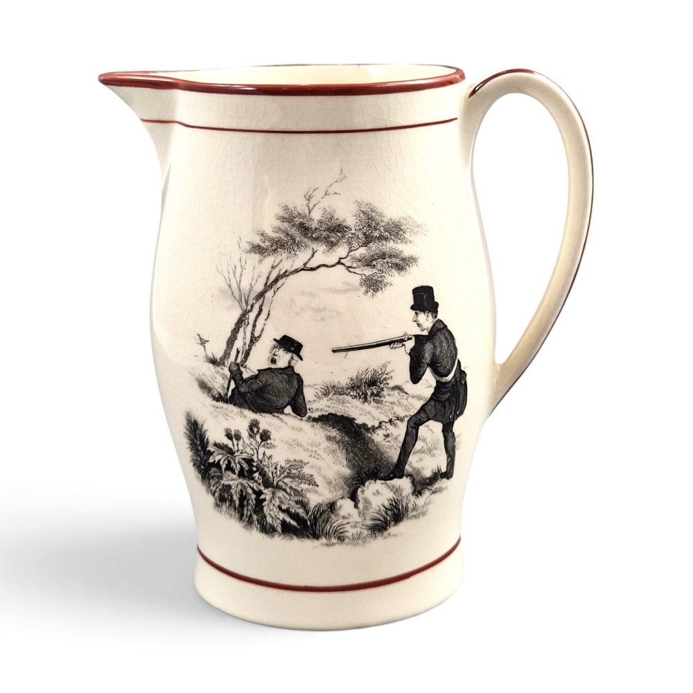 A Georgian creamware jug featuring a black transfer-printed hunting scene and terracotta red painted rim accents against a cream glaze.