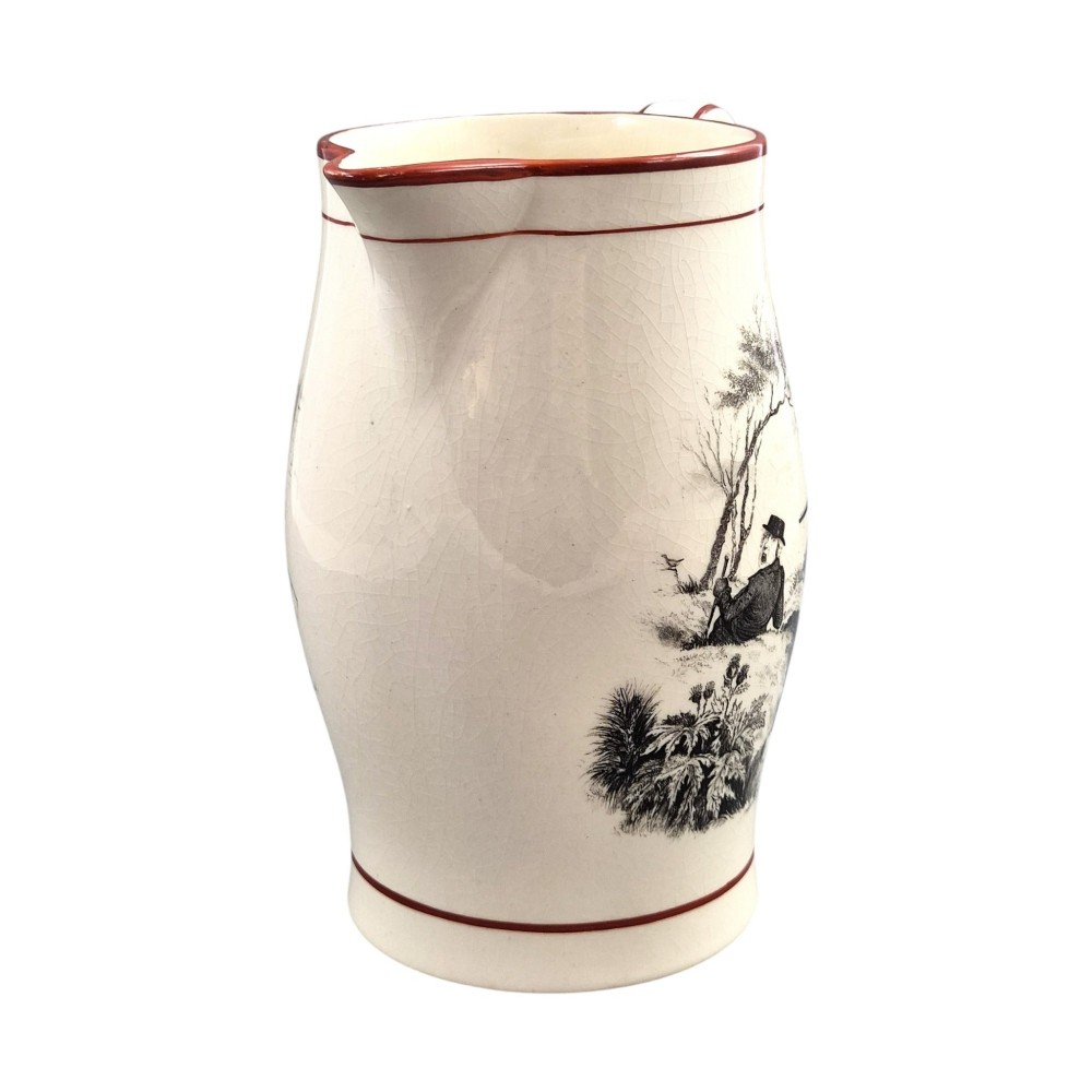 A Georgian creamware jug featuring a black transfer-printed hunting scene and terracotta red painted rim accents against a cream glaze. View II