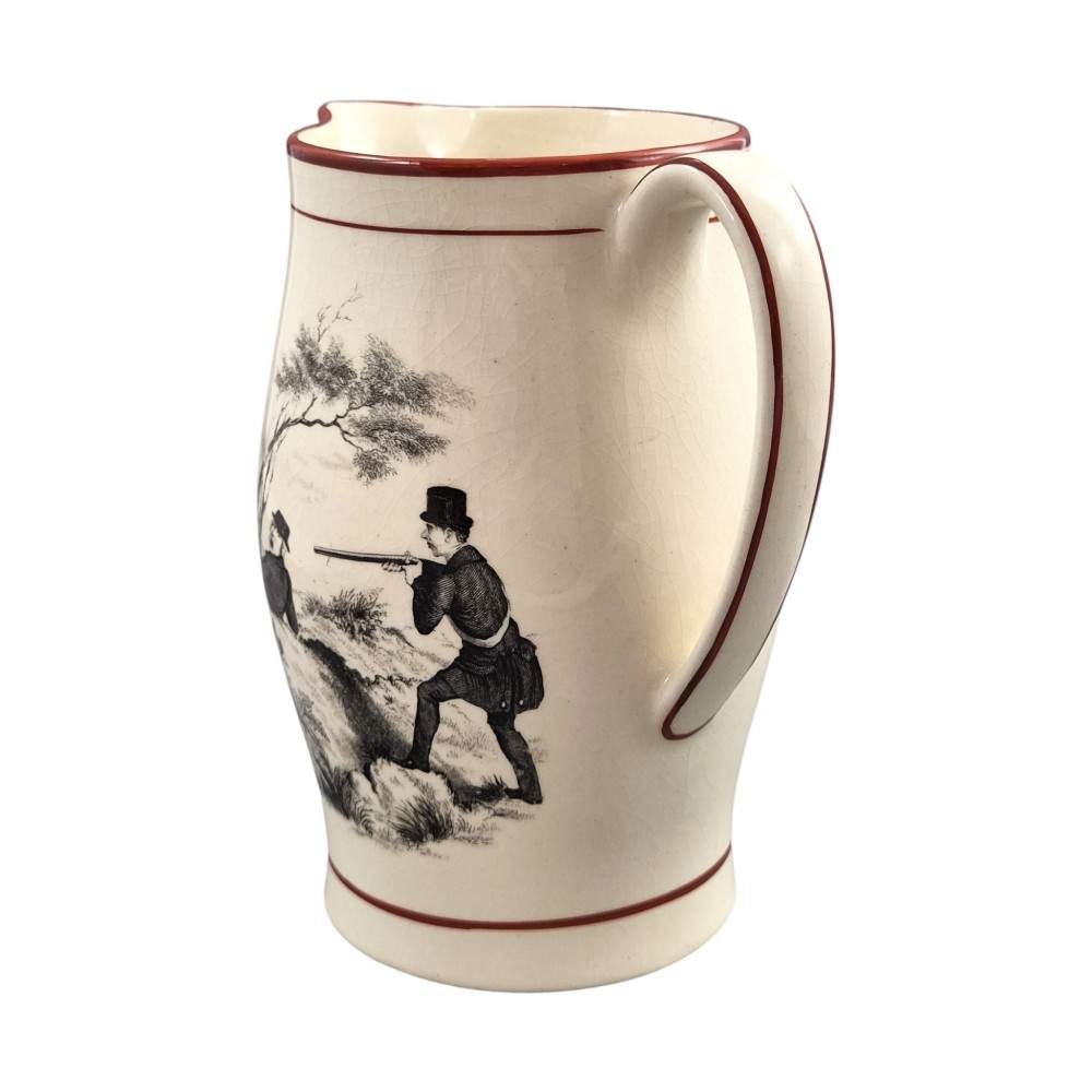 A Georgian creamware jug featuring a black transfer-printed hunting scene and terracotta red painted rim accents against a cream glaze. View VI