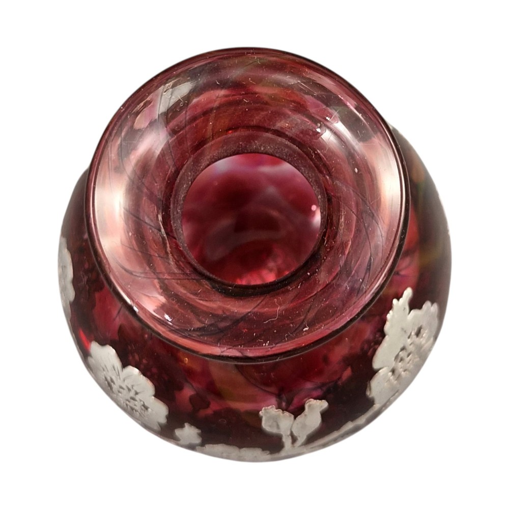 A three-piece ruby red glass vanity set featuring floral sterling silver overlay details across two stoppered bottles and a cylindrical beaker. View III