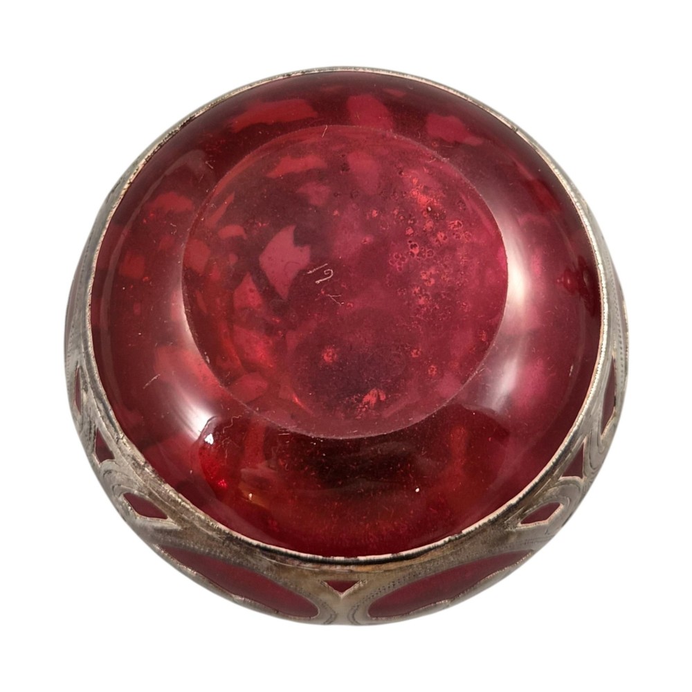 A three-piece ruby red glass vanity set featuring floral sterling silver overlay details across two stoppered bottles and a cylindrical beaker. View XIV