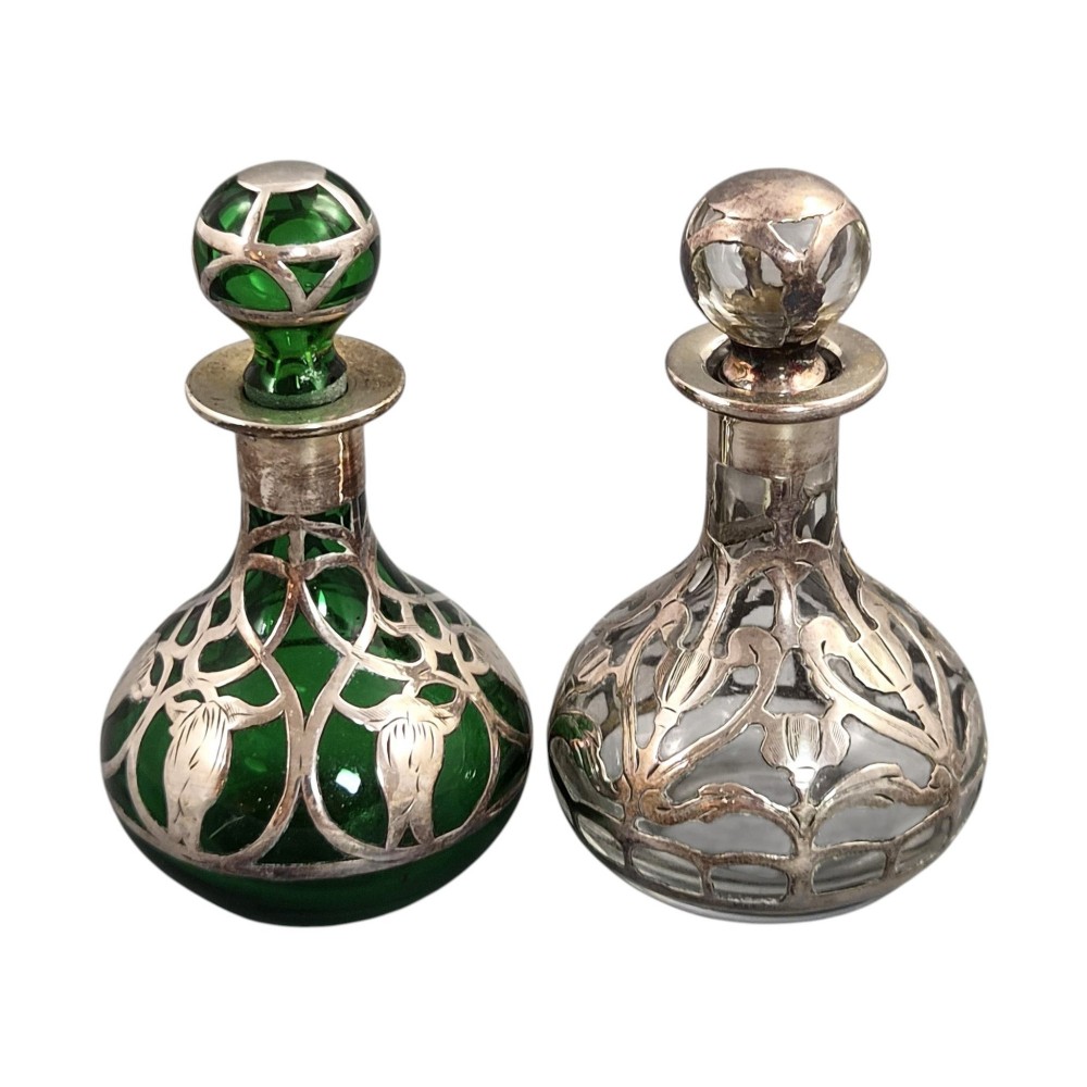 A pair of Art Nouveau perfume bottles featuring detailed sterling silver overlay in intricate floral lattice patterns on green and clear glass bases with matching glass stoppers. View II
