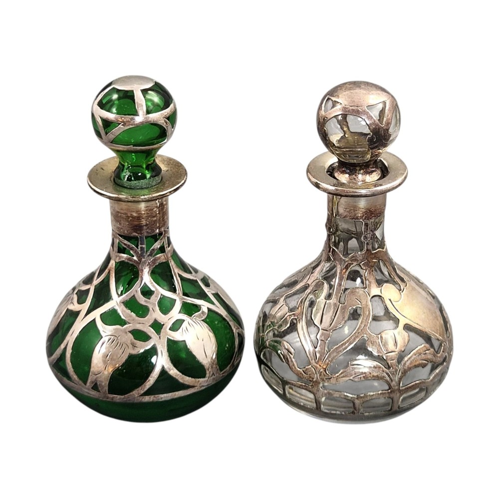 A pair of Art Nouveau perfume bottles featuring detailed sterling silver overlay in intricate floral lattice patterns on green and clear glass bases with matching glass stoppers. View III
