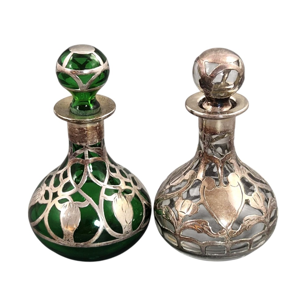 A pair of Art Nouveau perfume bottles featuring detailed sterling silver overlay in intricate floral lattice patterns on green and clear glass bases with matching glass stoppers. View IV