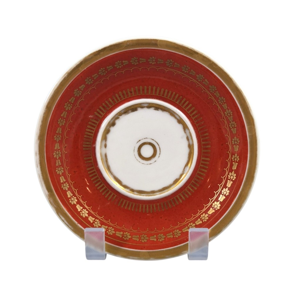 A red and gilded French Empire porcelain cabinet cup and matching saucer featuring a raised white lion mask handle detail. View II