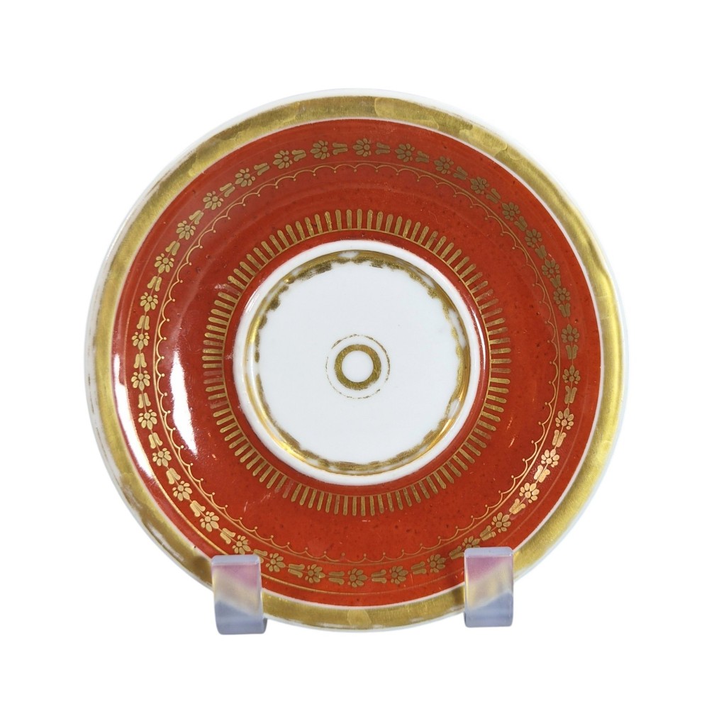 A red and gilded French Empire porcelain cabinet cup and matching saucer featuring a raised white lion mask handle detail. View III