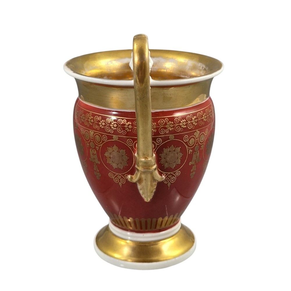 A red and gilded French Empire porcelain cabinet cup and matching saucer featuring a raised white lion mask handle detail. View VII