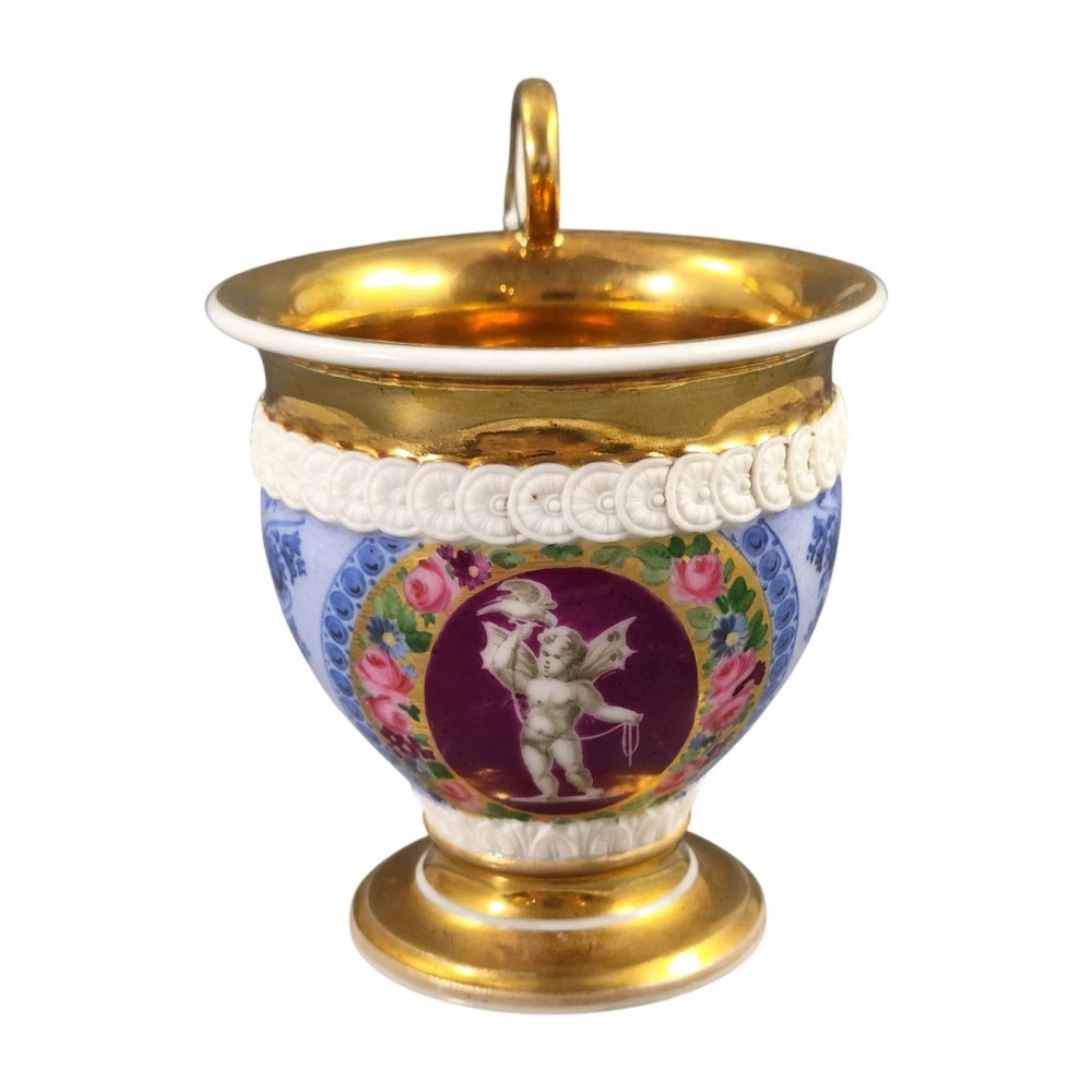 A nineteenth-century French Vieux Paris porcelain cabinet cup and matching saucer featuring gold gilding, multi-coloured hand-painted panels, and a high-loop lion mask handle. View XI