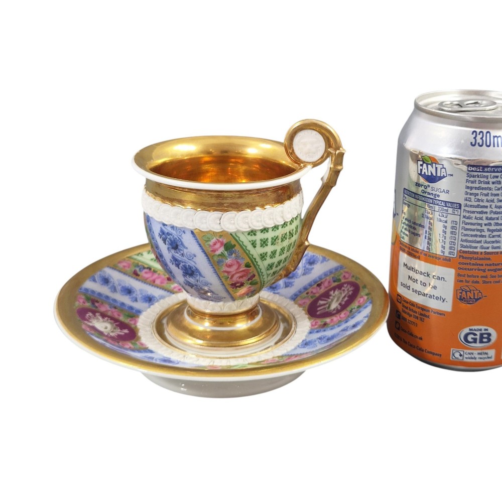 A nineteenth-century French Vieux Paris porcelain cabinet cup and matching saucer featuring gold gilding, multi-coloured hand-painted panels, and a high-loop lion mask handle. View XIV