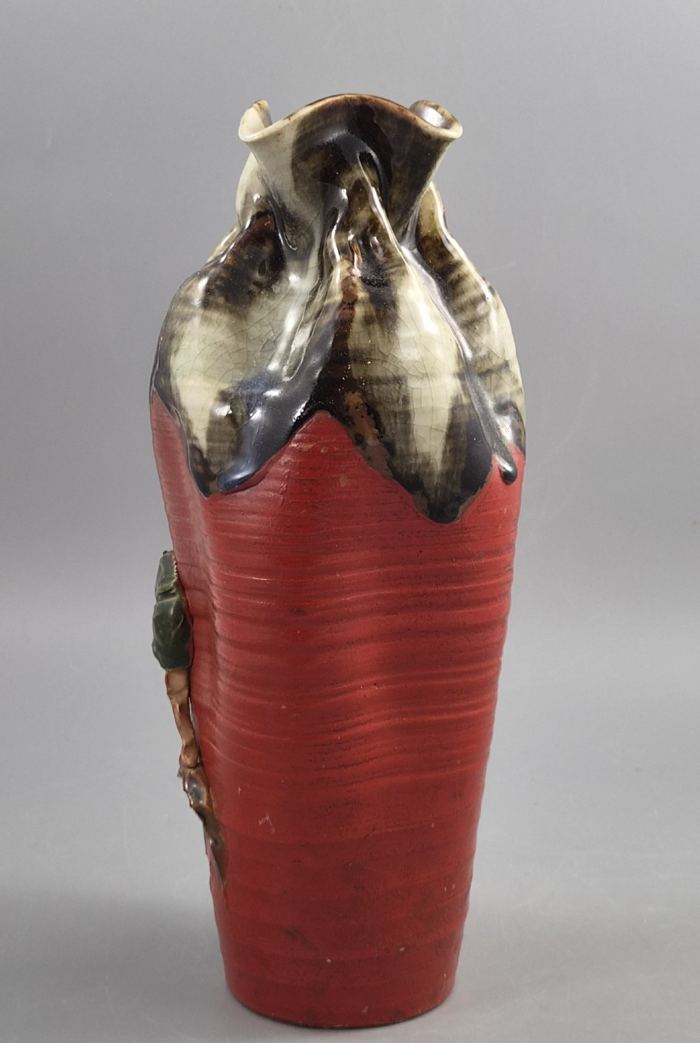 A tall Japanese Sumida Gawa ceramic vase featuring a ribbed red body, applied figures of climbing men, and a heavy flambe glaze around a pinched rim. View III