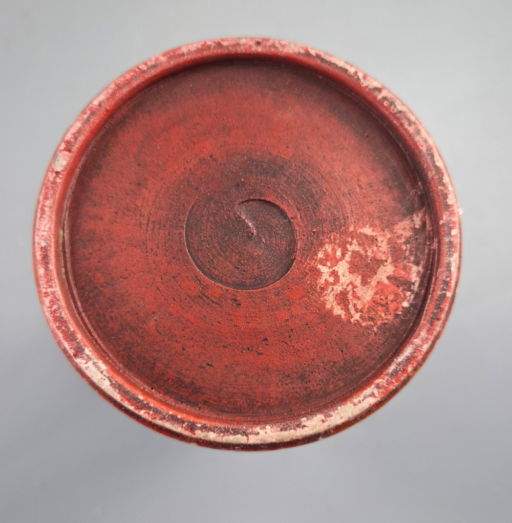 A tall Japanese Sumida Gawa ceramic pitcher featuring a ribbed terracotta body with relief figures pouring sake and a dark drip glaze near the lip. View XII