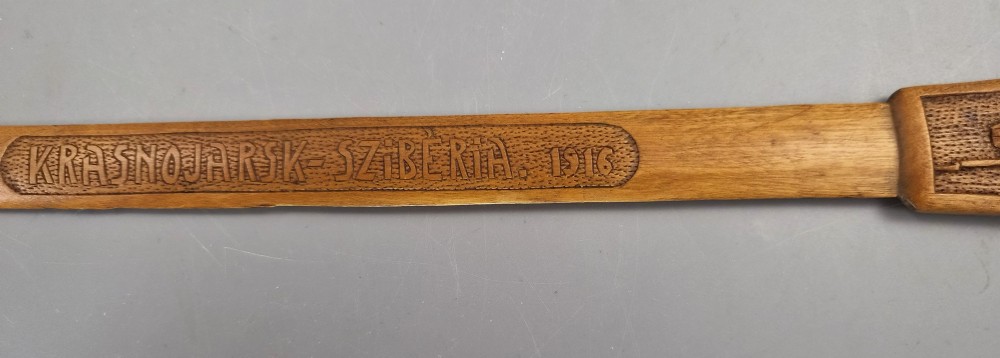 A hand-carved wooden letter opener featuring a relief carving of a soldier on the handle and carved text reading Krasnojarsk Sziberia 1916 on the blade. View V