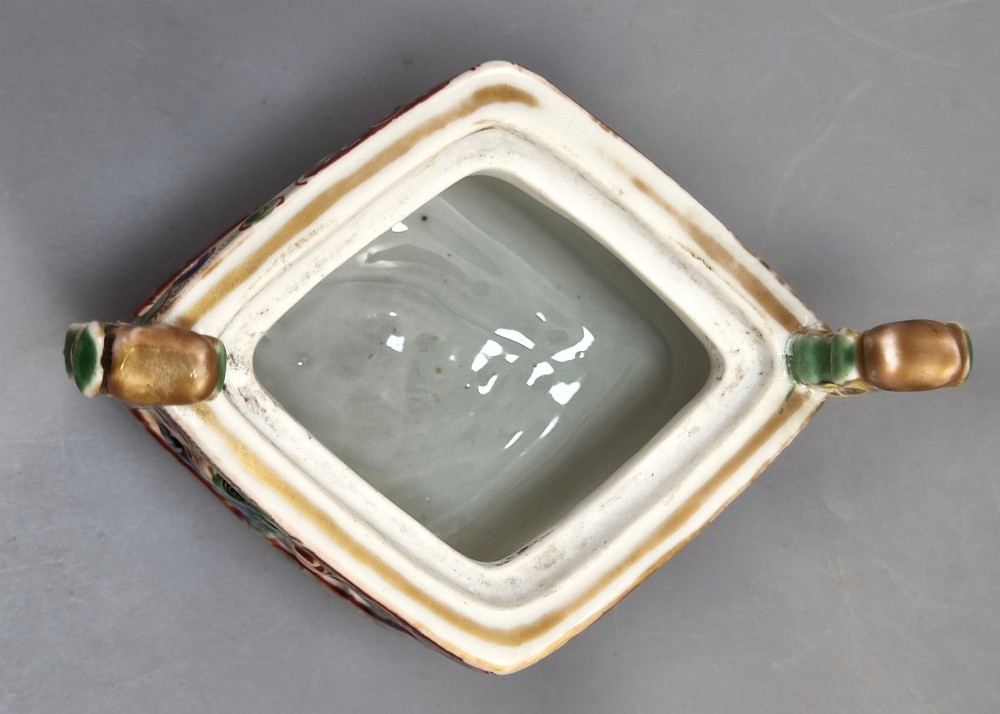 A square Japanese Kutani porcelain incense burner featuring a karashishi lion finial on the lid, hand-painted figural panels, and blue elephant-head legs. View V