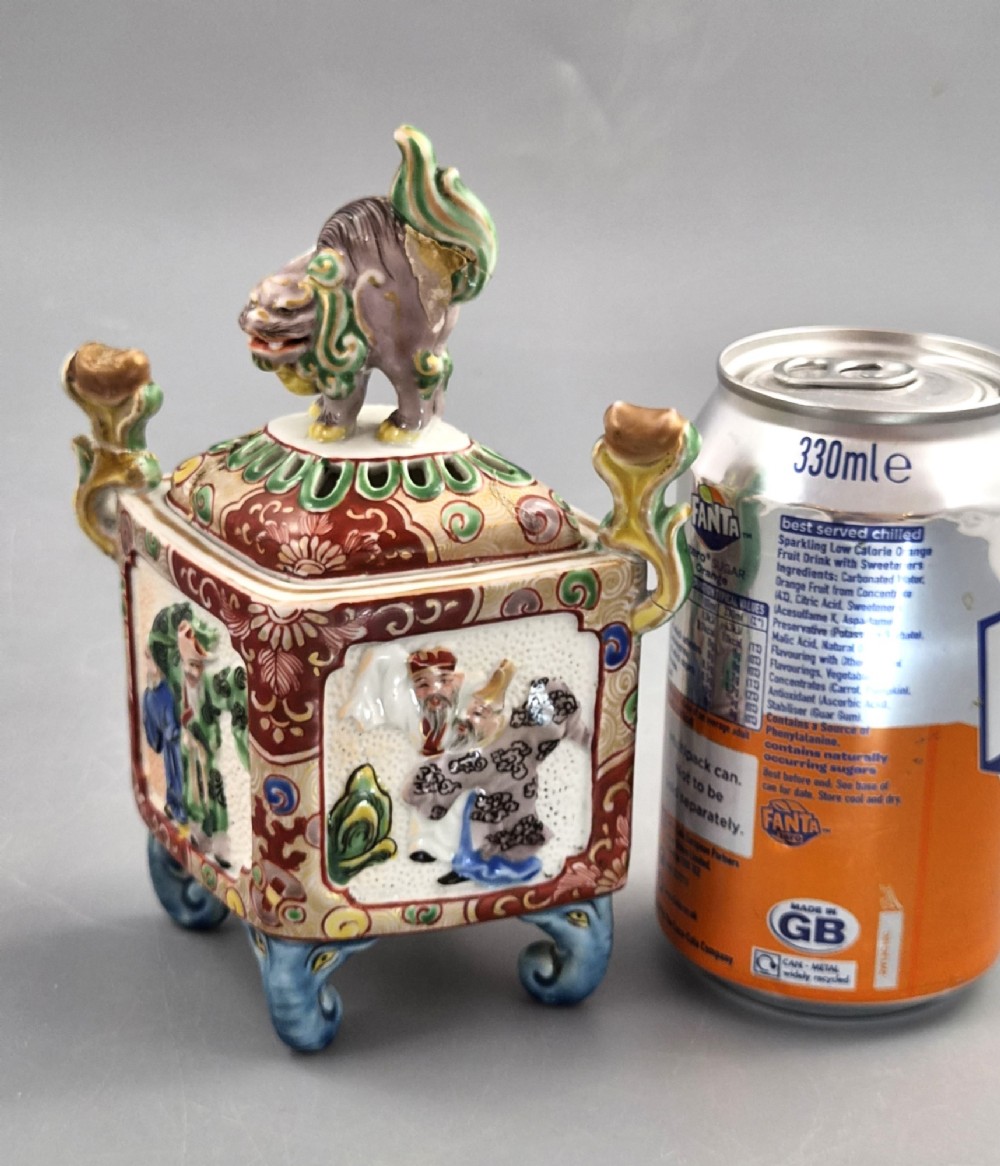 A square Japanese Kutani porcelain incense burner featuring a karashishi lion finial on the lid, hand-painted figural panels, and blue elephant-head legs. View XII