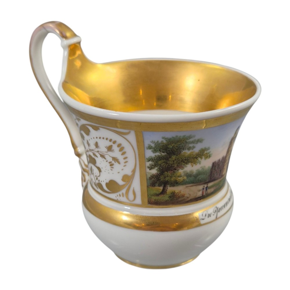 A 19th-century KPM Berlin porcelain cabinet cup with a fully gilded interior, high curved loop handle, and hand-painted topographical view of Peacock Island. View VII