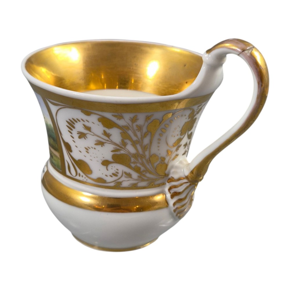 A 19th-century KPM Berlin porcelain cabinet cup with a fully gilded interior, high curved loop handle, and hand-painted topographical view of Peacock Island. View IX