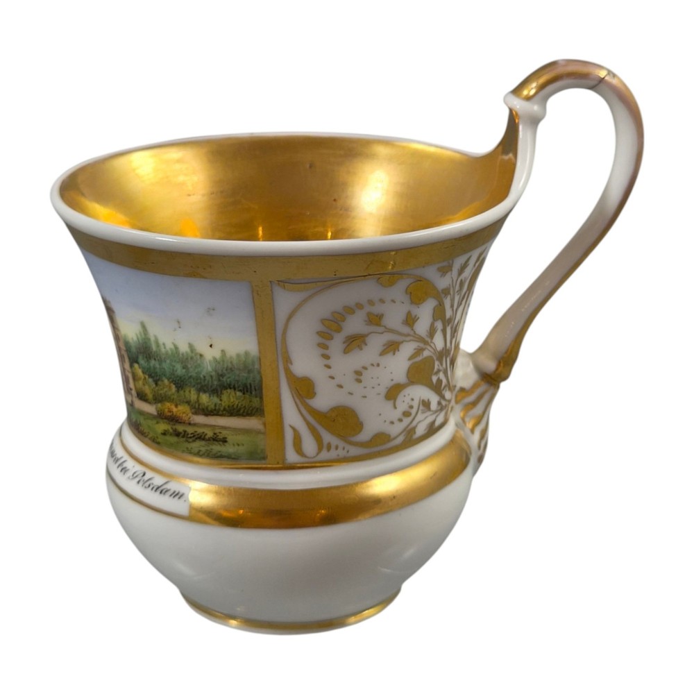 A 19th-century KPM Berlin porcelain cabinet cup with a fully gilded interior, high curved loop handle, and hand-painted topographical view of Peacock Island. View XII