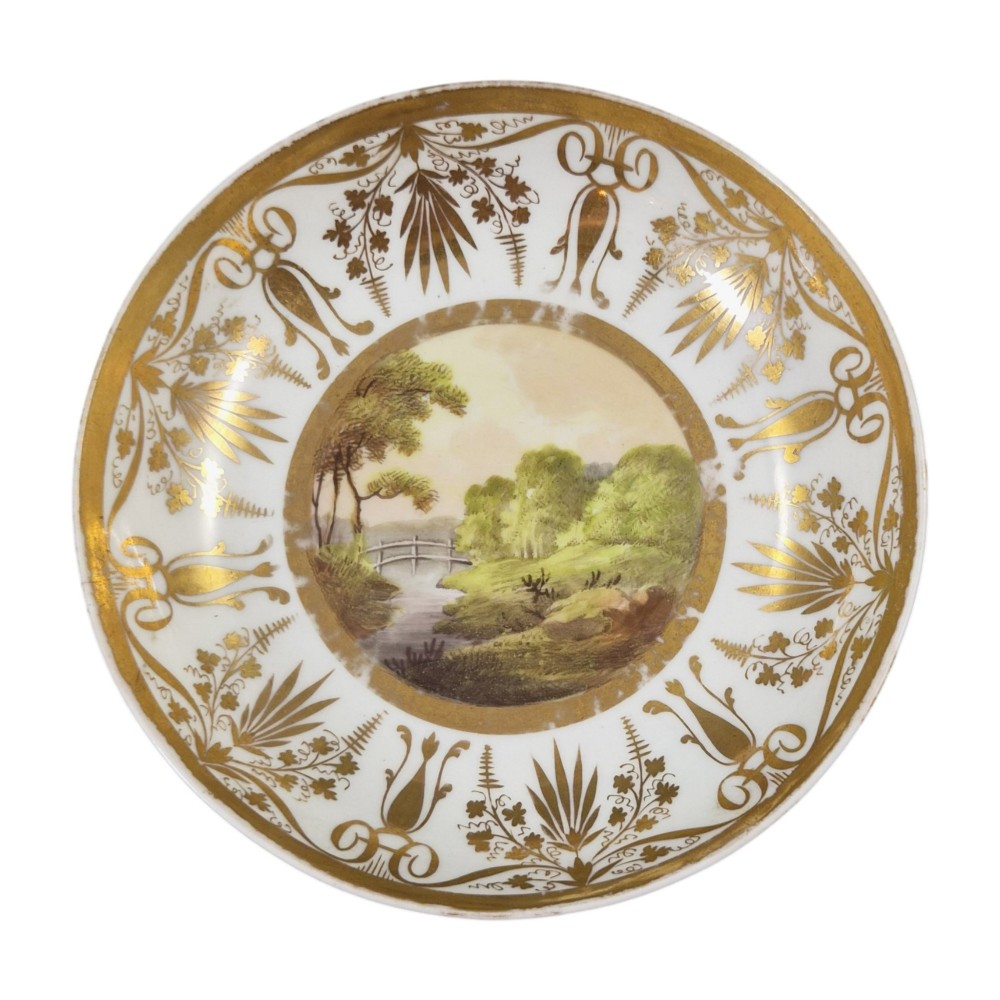 An early nineteenth-century KPM Berlin porcelain cabinet cup and saucer decorated with gilt foliage patterns and hand-painted landscape scenes. View II