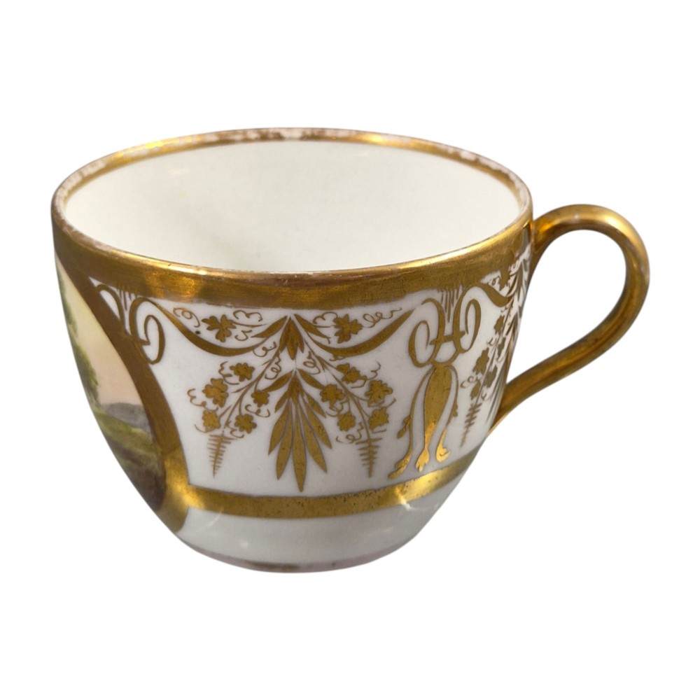 An early nineteenth-century KPM Berlin porcelain cabinet cup and saucer decorated with gilt foliage patterns and hand-painted landscape scenes. View V