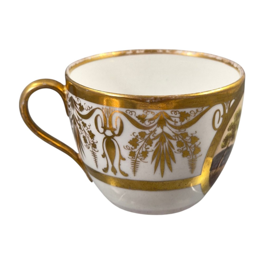 An early nineteenth-century KPM Berlin porcelain cabinet cup and saucer decorated with gilt foliage patterns and hand-painted landscape scenes. View VII
