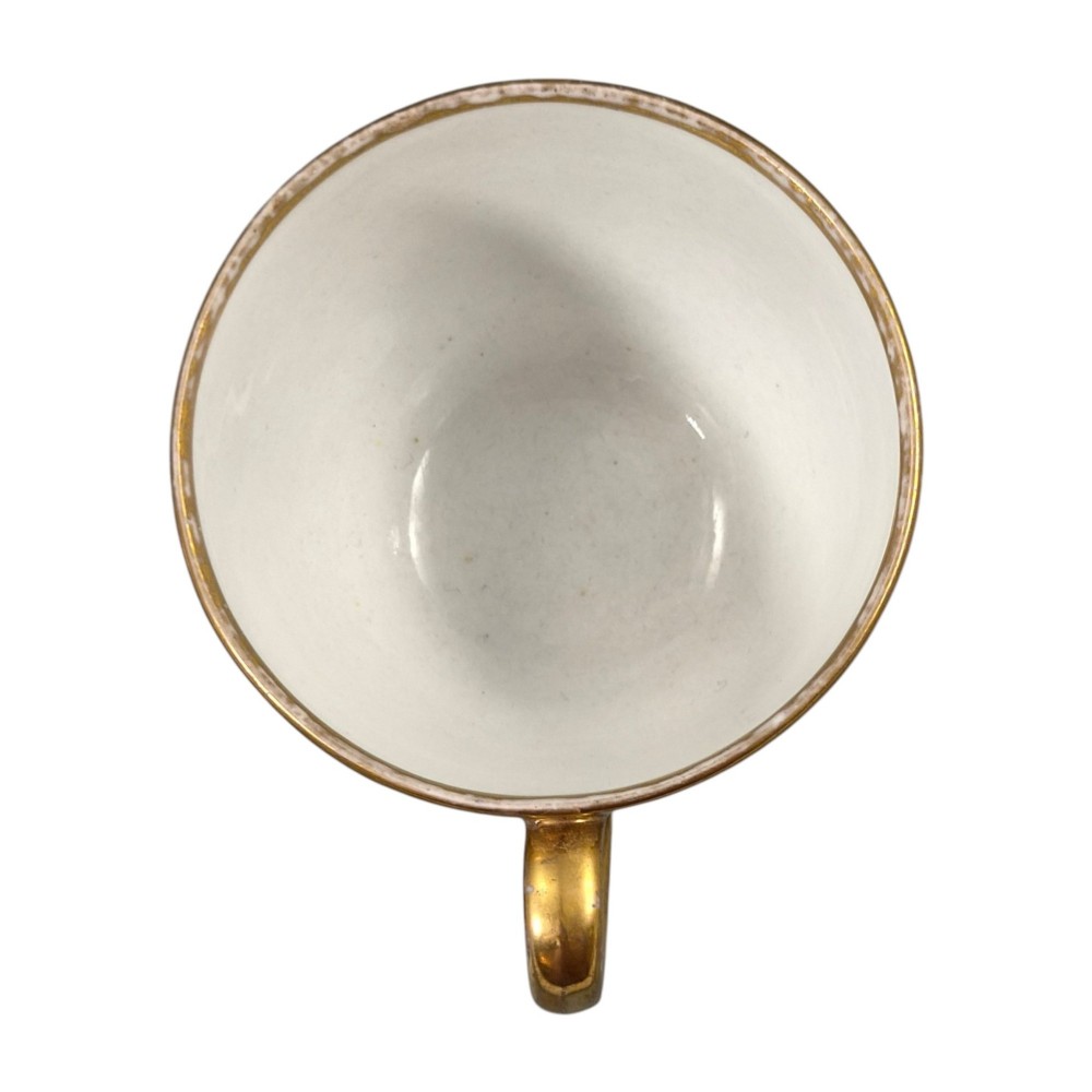 An early nineteenth-century KPM Berlin porcelain cabinet cup and saucer decorated with gilt foliage patterns and hand-painted landscape scenes. View IX