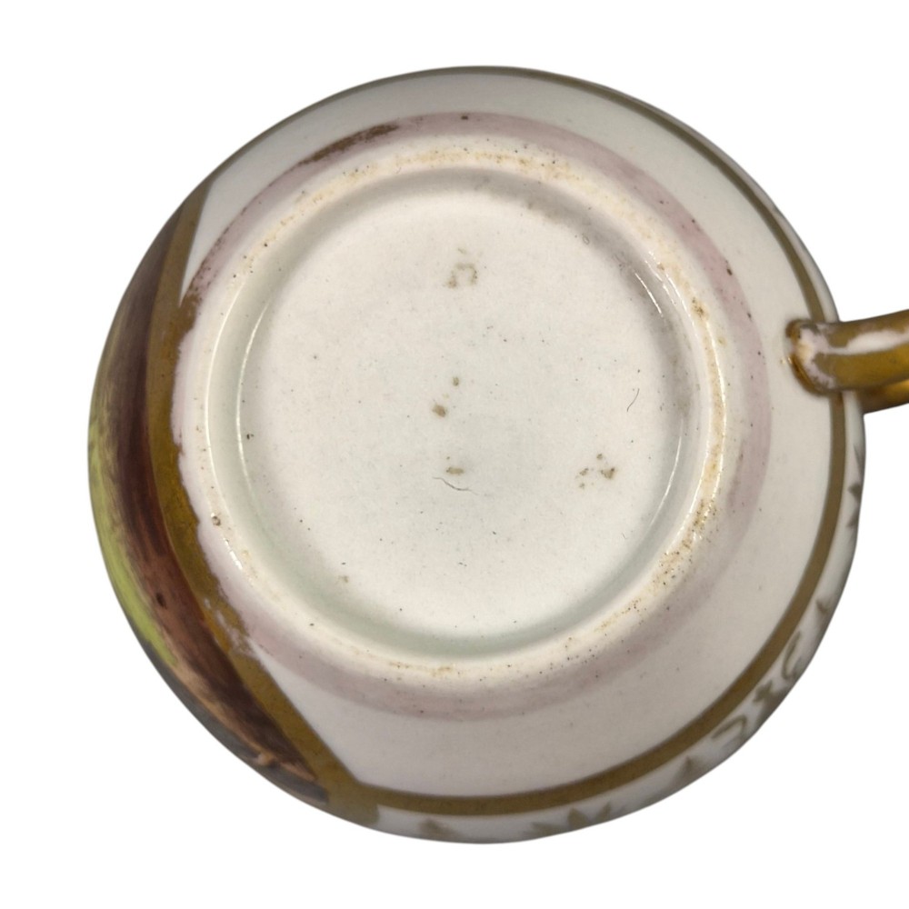 An early nineteenth-century KPM Berlin porcelain cabinet cup and saucer decorated with gilt foliage patterns and hand-painted landscape scenes. View X
