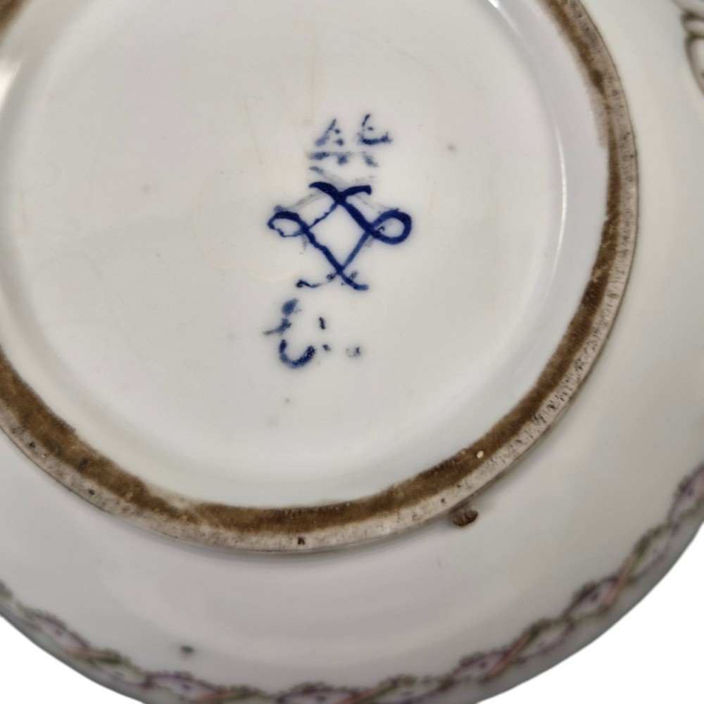 A white Sevres porcelain teapot featuring polychrome geometric enamel borders, gilt trim, a rounded body, and a gilded spherical lid finial. View IX