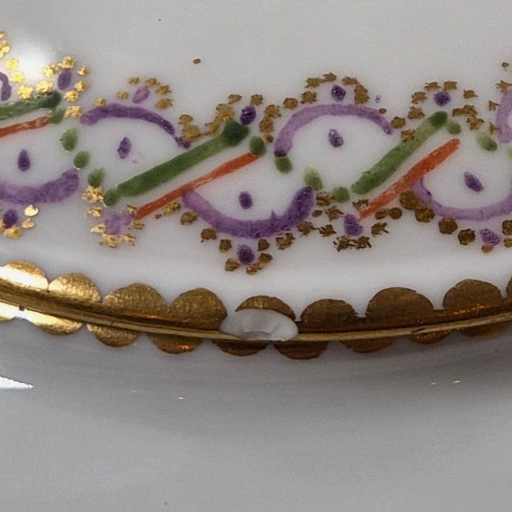 A white Sevres porcelain teapot featuring polychrome geometric enamel borders, gilt trim, a rounded body, and a gilded spherical lid finial. View XIII