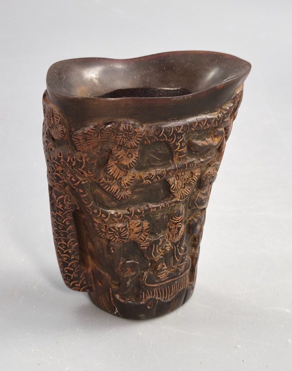 A dark brown carved water buffalo horn libation cup featuring relief carvings of immortals standing under pine trees. View III