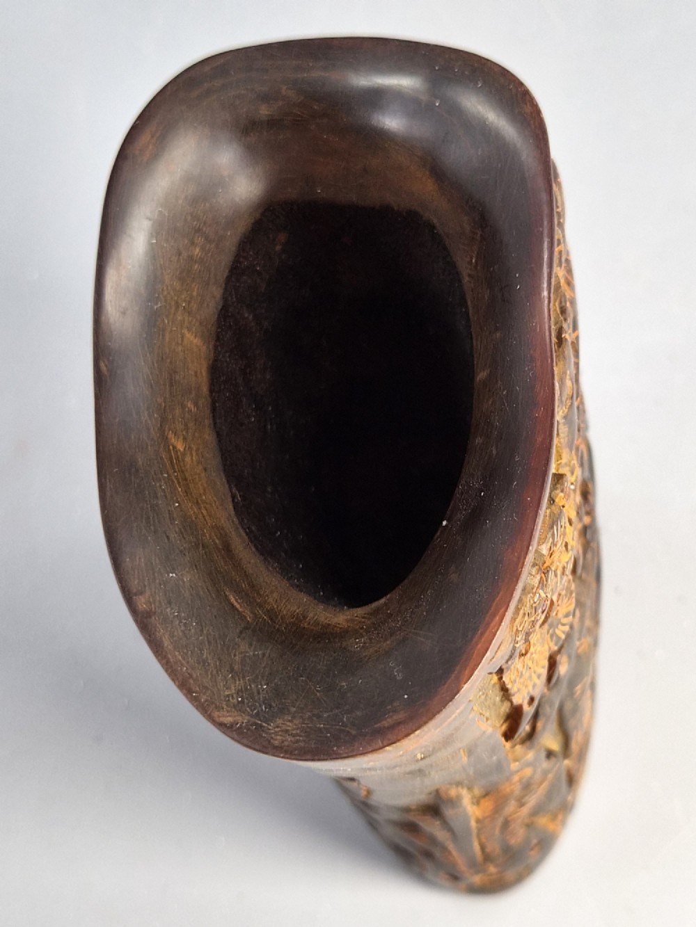A dark brown carved water buffalo horn libation cup featuring relief carvings of immortals standing under pine trees. View VII