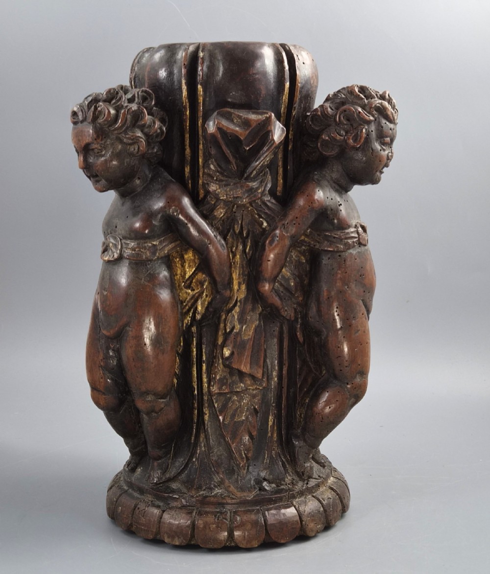 A dark carved walnut Italian Baroque torchiere base featuring three sculpted putti figures standing around a central fluted shaft on a gadrooned circular base. View IV