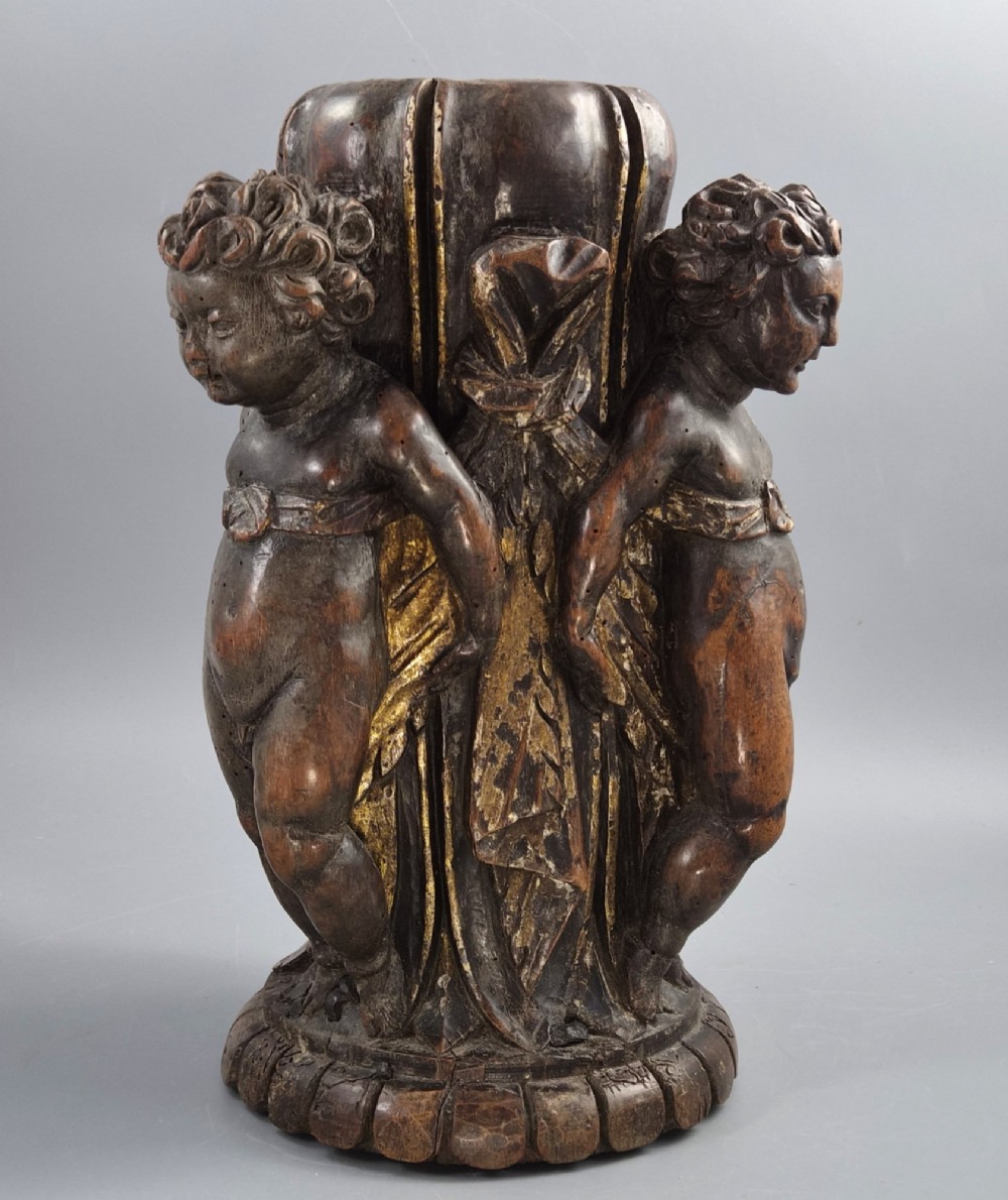 A dark carved walnut Italian Baroque torchiere base featuring three sculpted putti figures standing around a central fluted shaft on a gadrooned circular base. View VIII