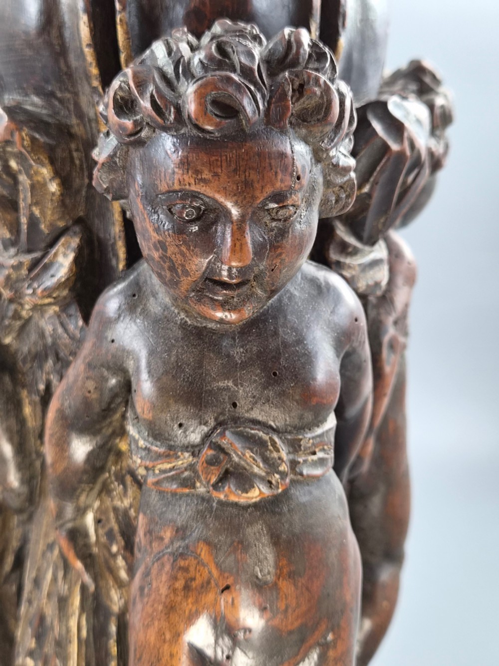 A dark carved walnut Italian Baroque torchiere base featuring three sculpted putti figures standing around a central fluted shaft on a gadrooned circular base. View XII