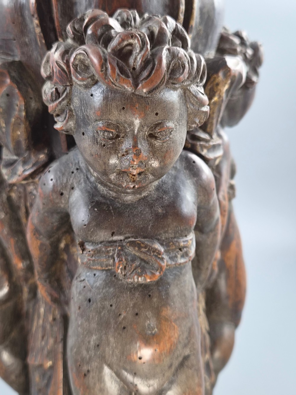 A dark carved walnut Italian Baroque torchiere base featuring three sculpted putti figures standing around a central fluted shaft on a gadrooned circular base. View XIII
