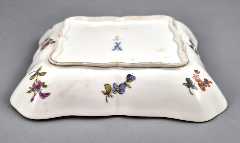 A square shaped Meissen porcelain dish decorated with hand-painted Watteau scenes, floral reserves on a black ground, and gilded scroll borders. View VIII
