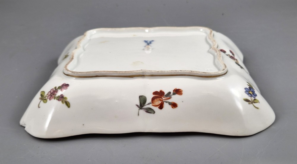 A square shaped Meissen porcelain dish decorated with hand-painted Watteau scenes, floral reserves on a black ground, and gilded scroll borders. View X