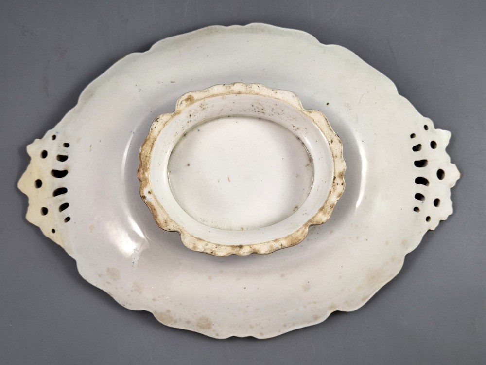 An oval porcelain dish featuring a dark cobalt blue rim with gold scrollwork, reticulated handles, floral panels, and a central hand-painted scene of colorful birds perched on branches. View X