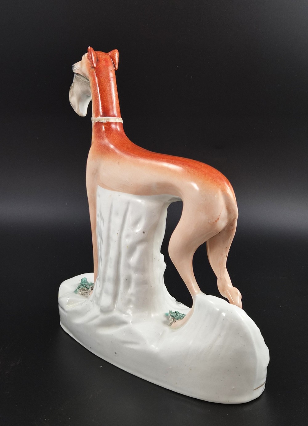 A pair of antique Victorian Staffordshire earthenware figures depicting standing orange greyhounds holding grey hares in their jaws on white bases. View VIII