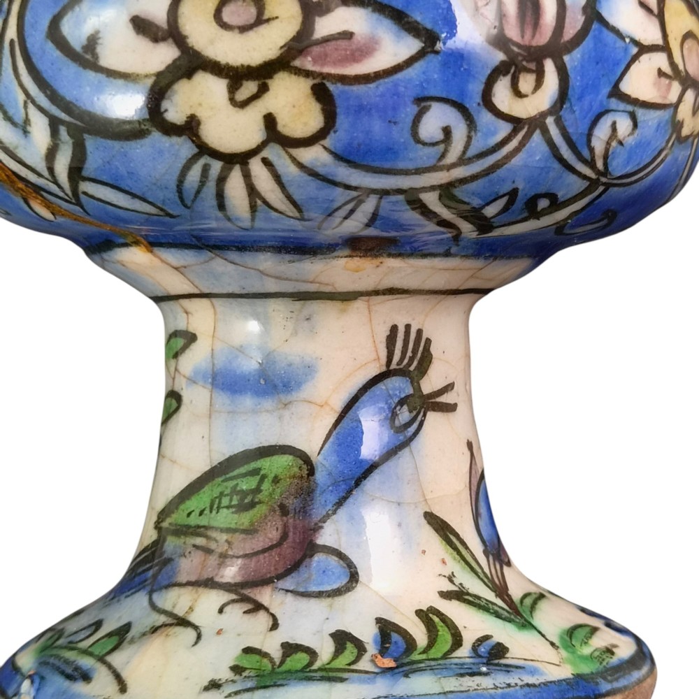 A late Qajar Persian polychrome ceramic vase featuring a central bulbous knop, flared rim, crackle glaze finish, and painted blue and green floral motifs. View X