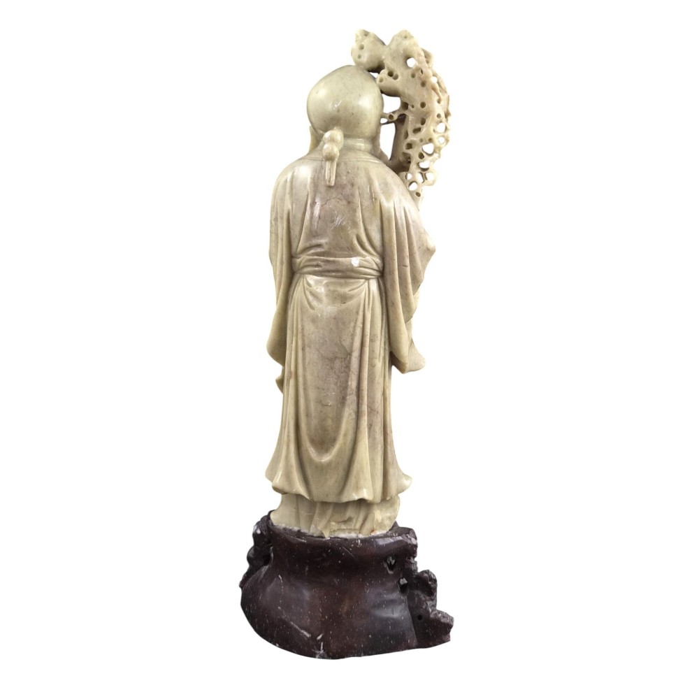 A late 19th-century carved pale soapstone figure of Shoulao holding a peach and staff, standing on a dark stone pierced rockwork base. View IV