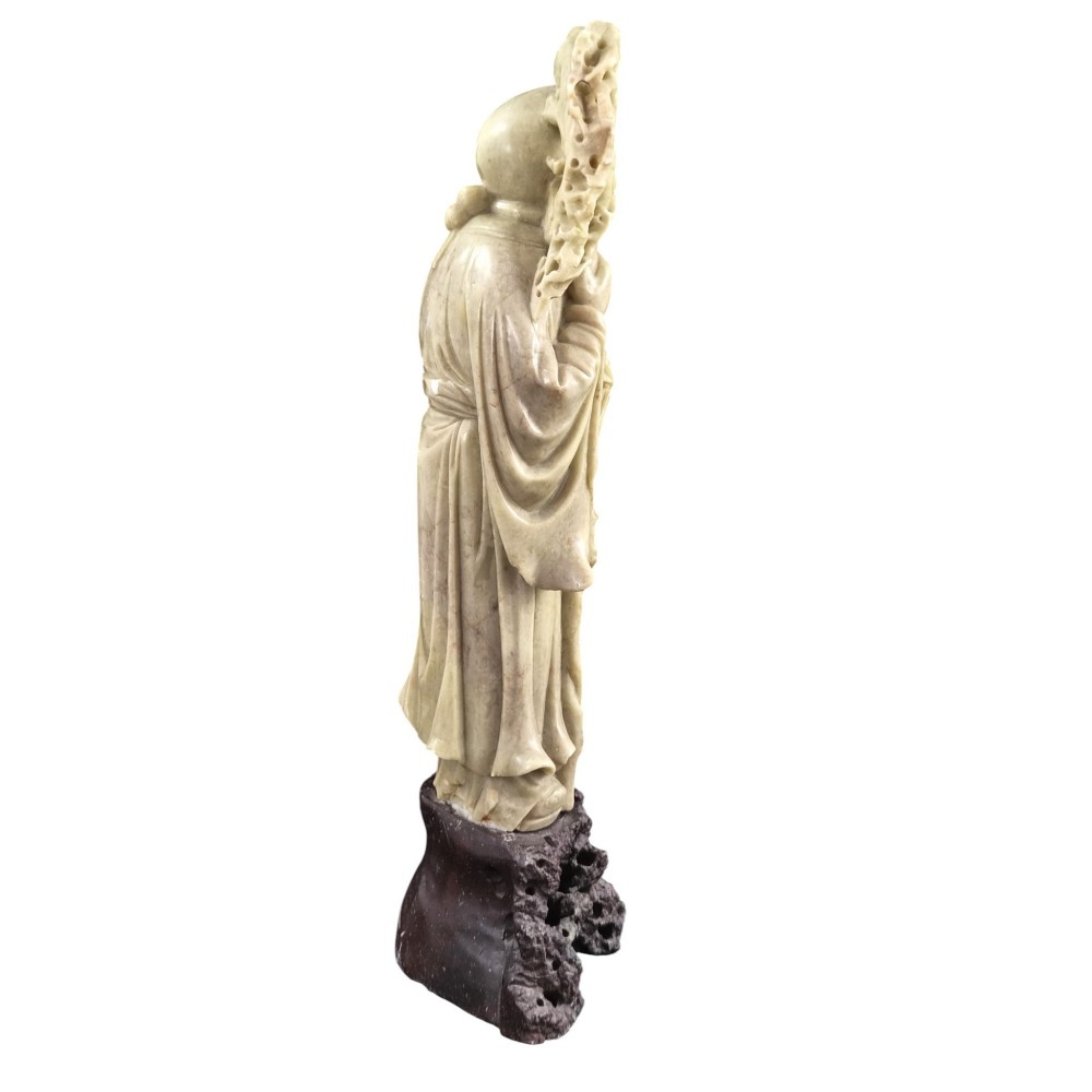 A late 19th-century carved pale soapstone figure of Shoulao holding a peach and staff, standing on a dark stone pierced rockwork base. View V