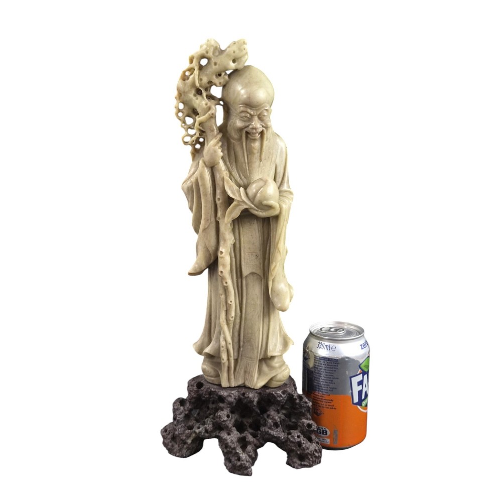 A late 19th-century carved pale soapstone figure of Shoulao holding a peach and staff, standing on a dark stone pierced rockwork base. View VII