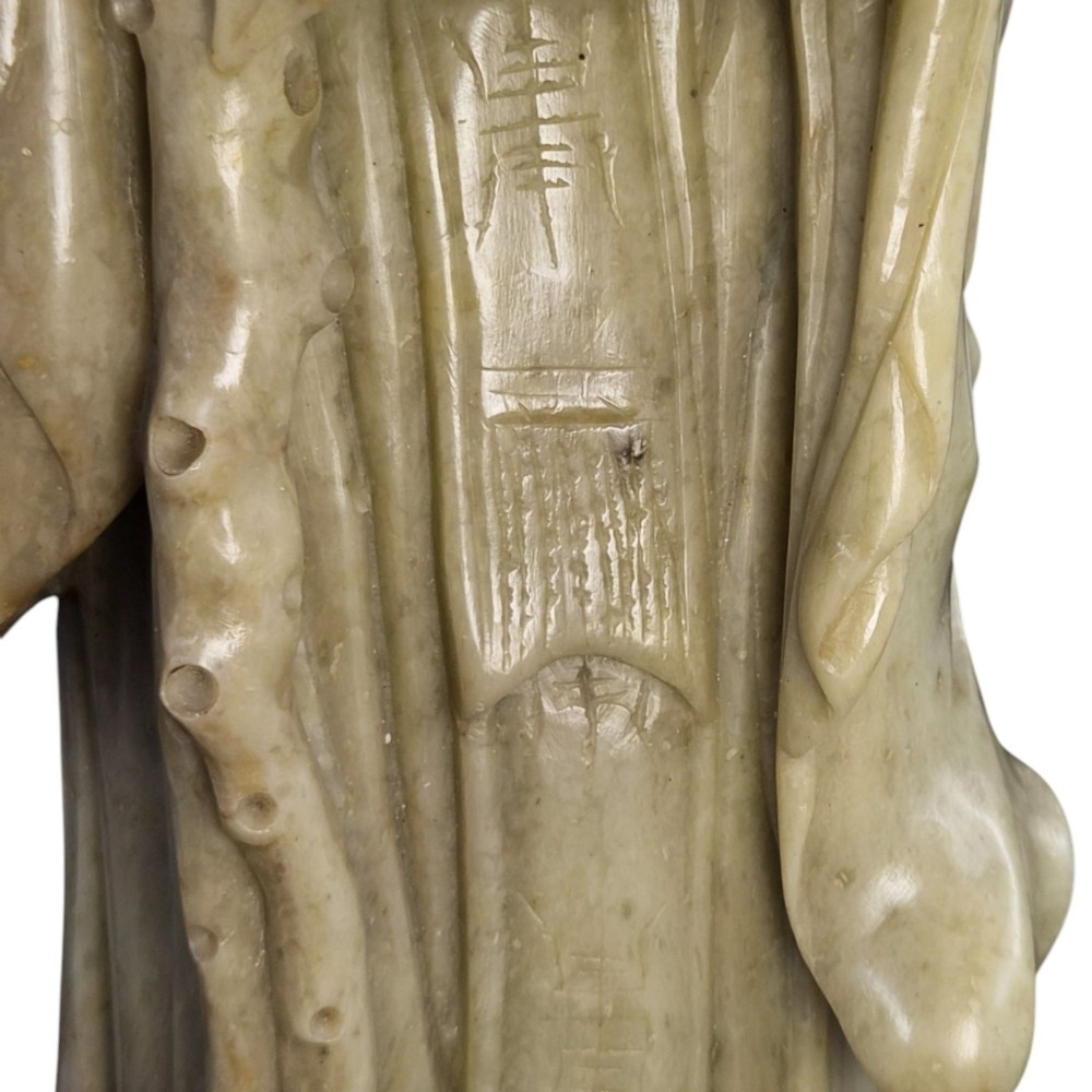 A late 19th-century carved pale soapstone figure of Shoulao holding a peach and staff, standing on a dark stone pierced rockwork base. View X