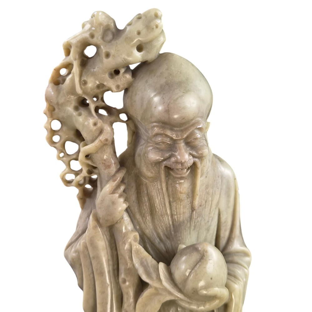 A late 19th-century carved pale soapstone figure of Shoulao holding a peach and staff, standing on a dark stone pierced rockwork base. View XI