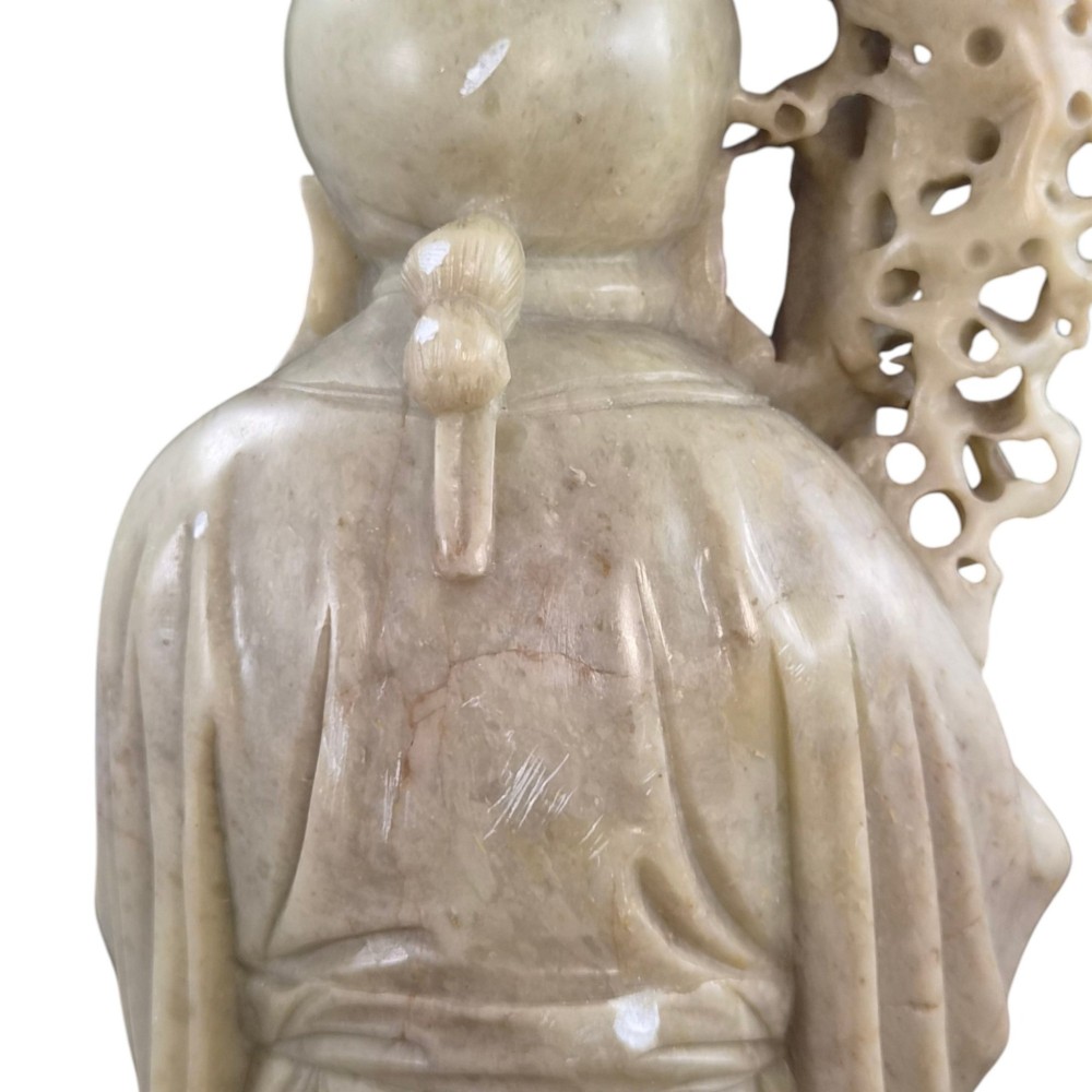 A late 19th-century carved pale soapstone figure of Shoulao holding a peach and staff, standing on a dark stone pierced rockwork base. View XIII