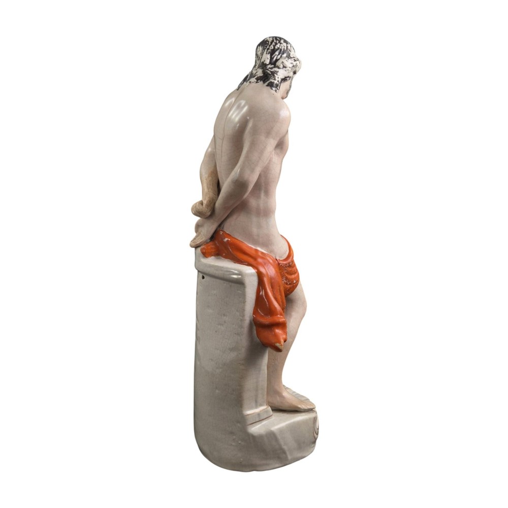 A Victorian earthenware figurine depicting Christ standing at a column draped in a terracotta-coloured cloth on a scrollwork base. View II