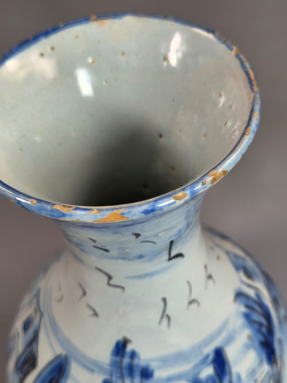 An antique bulbous blue and white maiolica ceramic vase decorated with a hand-painted architectural landscape scene and a flared rim. View X