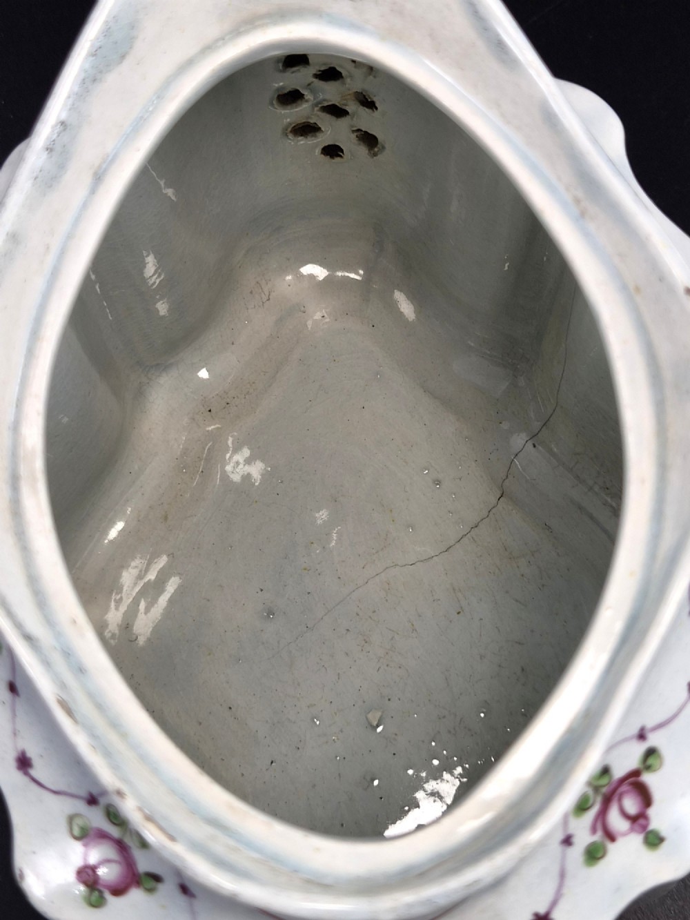An off-white earthenware commode-shaped teapot decorated with hand-painted floral sprays, red borders, and a seated widow finial on the lid. View VII