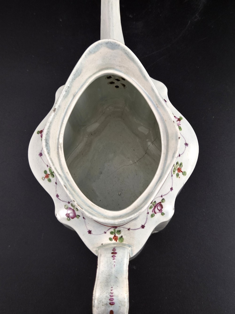 An off-white earthenware commode-shaped teapot decorated with hand-painted floral sprays, red borders, and a seated widow finial on the lid. View VIII